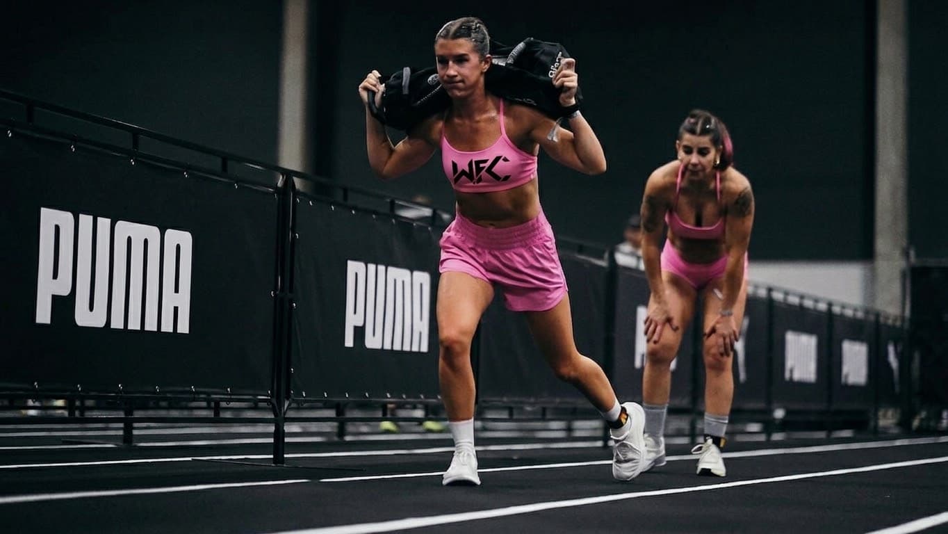 Two athletes in pink training with sandbags during a HYROX race
